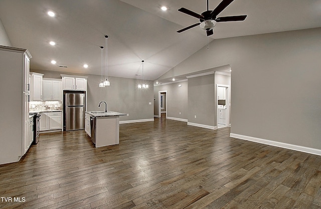 kitchen with decorative light fixtures, sink, white cabinets, stainless steel fridge, and a center island with sink