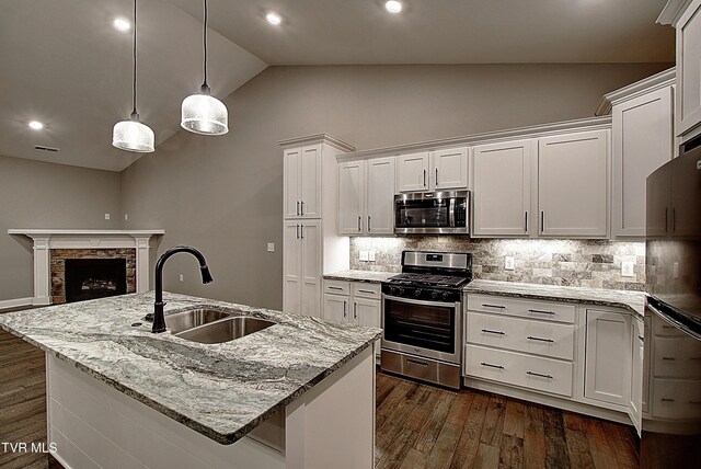 kitchen with white cabinetry, stainless steel appliances, sink, and a center island with sink