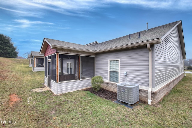 back of property with a sunroom, cooling unit, and a lawn