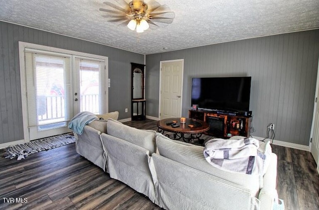 living room featuring ceiling fan, a textured ceiling, dark hardwood / wood-style flooring, and french doors