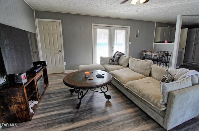 living room with a textured ceiling, dark wood-type flooring, french doors, and ceiling fan