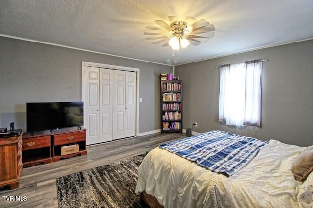 bedroom featuring wood-type flooring, ornamental molding, ceiling fan, and a closet