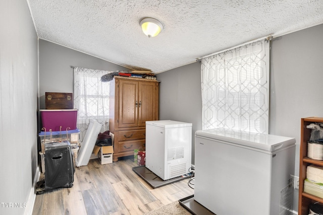 10955 Middle Wallens Creek Rd, Jonesville, VA 24263 - clothes washing area featuring light wood-type flooring, separate washer and dryer, a textured ceiling, and cabinet space