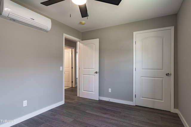 unfurnished bedroom featuring dark wood-style floors, a wall mounted air conditioner, a ceiling fan, and baseboards