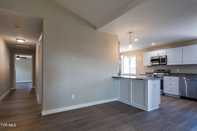 kitchen featuring hanging light fixtures, appliances with stainless steel finishes, dark wood-type flooring, white cabinets, and a peninsula