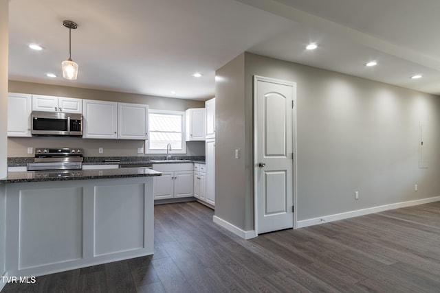 kitchen featuring stainless steel appliances, white cabinets, a sink, and hanging light fixtures