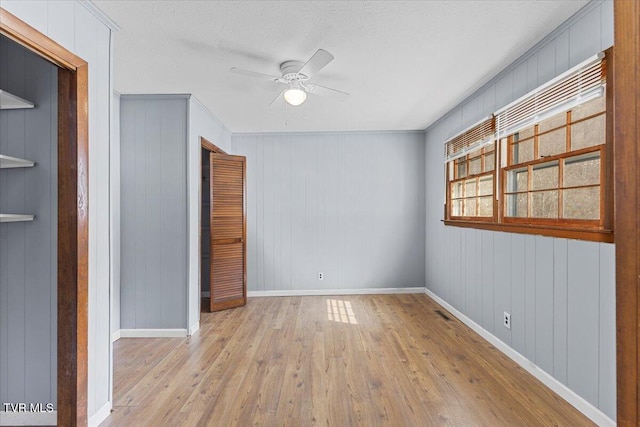 unfurnished bedroom with a ceiling fan, light wood-type flooring, a textured ceiling, and baseboards