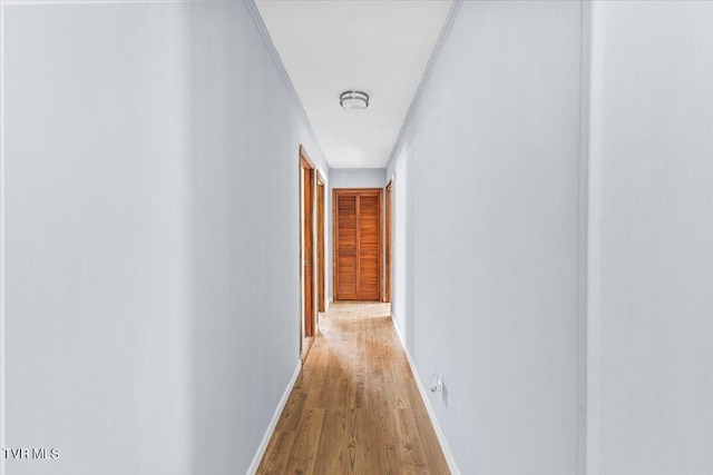 corridor with light wood-type flooring and baseboards