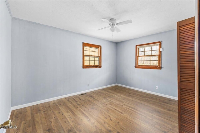 spare room with a ceiling fan, a wealth of natural light, and wood finished floors