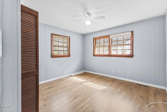 spare room featuring light wood-style flooring, visible vents, baseboards, and a ceiling fan