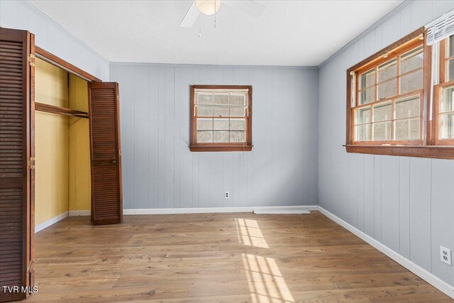 unfurnished bedroom with ceiling fan, a closet, wood finished floors, and baseboards