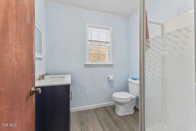 bathroom featuring crown molding, toilet, vanity, wood finished floors, and baseboards