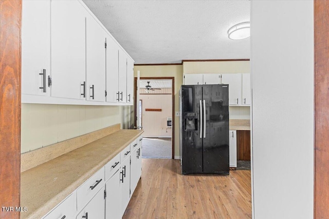 kitchen with light wood-style floors, light countertops, white cabinetry, and black refrigerator with ice dispenser