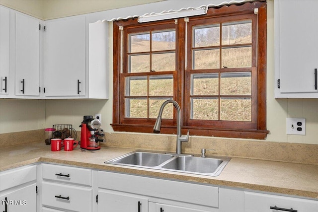 kitchen featuring light countertops, a sink, and white cabinets