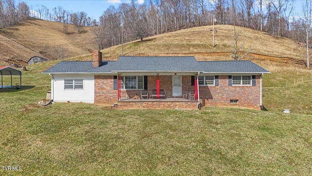 ranch-style house with a porch, brick siding, roof with shingles, a chimney, and a front yard