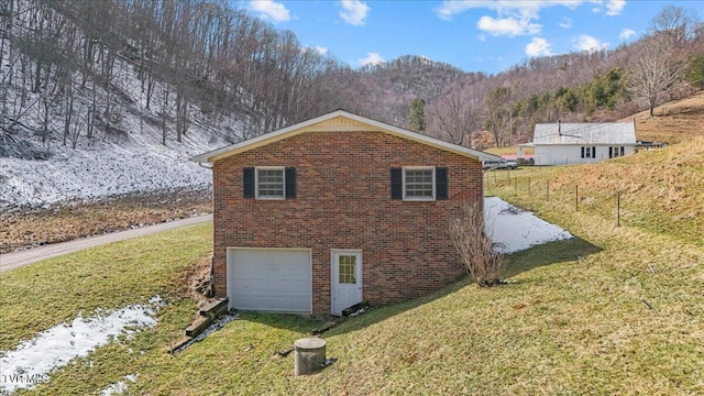 view of side of home featuring a garage, a yard, driveway, and brick siding