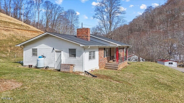 rear view of property featuring a shingled roof, a lawn, and a chimney