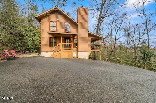 rustic home featuring aphalt driveway, crawl space, and a chimney