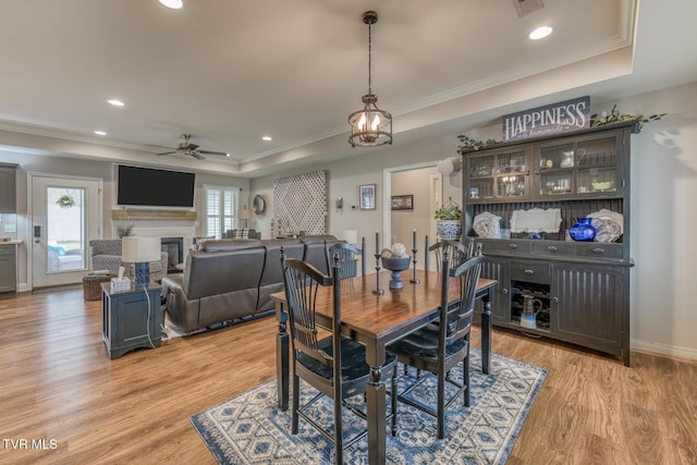 dining area featuring ceiling fan, light hardwood / wood-style floors, crown molding, and a raised ceiling