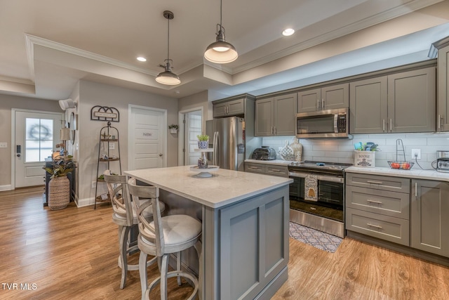 kitchen with light hardwood / wood-style flooring, a center island, pendant lighting, stainless steel appliances, and gray cabinets