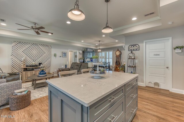 kitchen featuring hanging light fixtures, light hardwood / wood-style flooring, crown molding, and a kitchen island