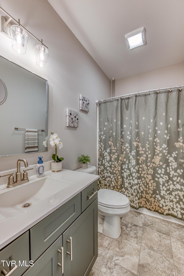 bathroom with toilet, a shower with shower curtain, and vanity