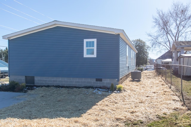 view of side of property featuring crawl space, fence, and central AC