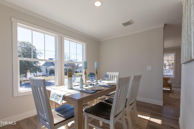 dining area featuring crown molding, plenty of natural light, visible vents, and dark wood finished floors