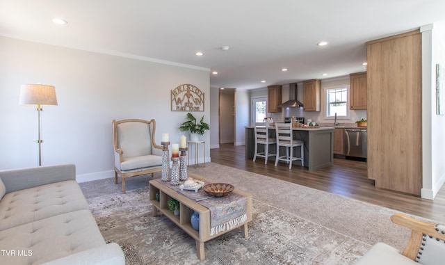 living area featuring baseboards, dark wood-type flooring, ornamental molding, and recessed lighting