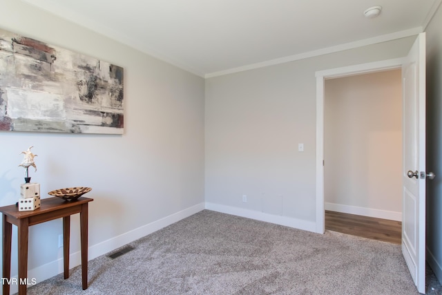 spare room with carpet floors, baseboards, visible vents, and ornamental molding