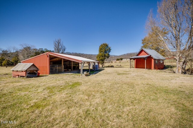 view of yard featuring a detached carport, a rural view, and an outdoor structure