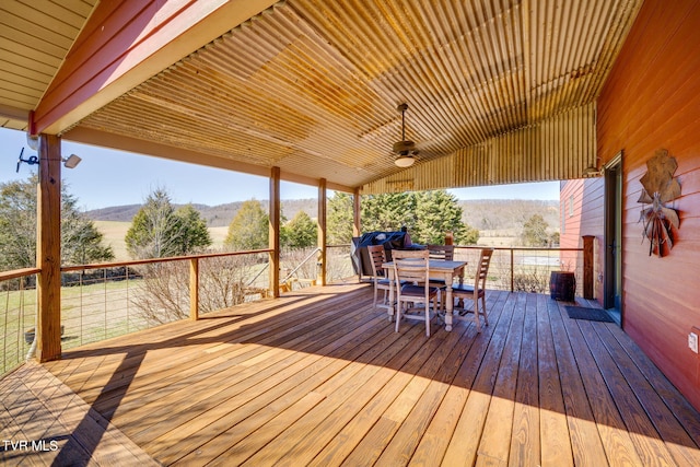 deck with a mountain view, outdoor dining area, and a ceiling fan