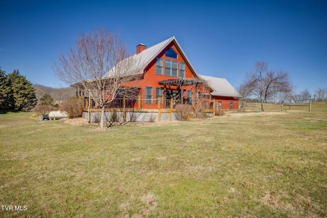 back of property with a deck, a lawn, and a chimney