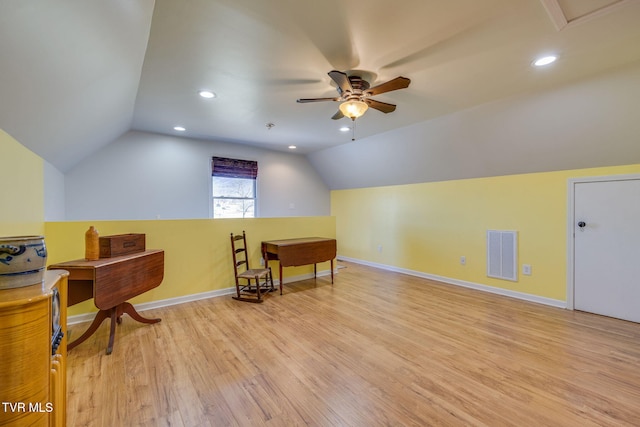 additional living space featuring light wood finished floors, baseboards, visible vents, a ceiling fan, and vaulted ceiling