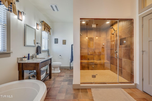 full bathroom featuring a freestanding tub, a shower stall, toilet, and vanity