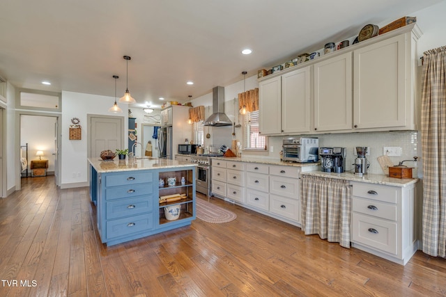 kitchen with wall chimney range hood, appliances with stainless steel finishes, and white cabinets