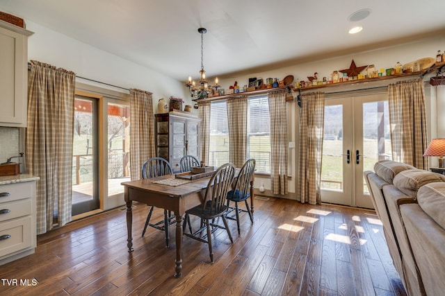 dining room with dark wood-style floors, recessed lighting, an inviting chandelier, and french doors