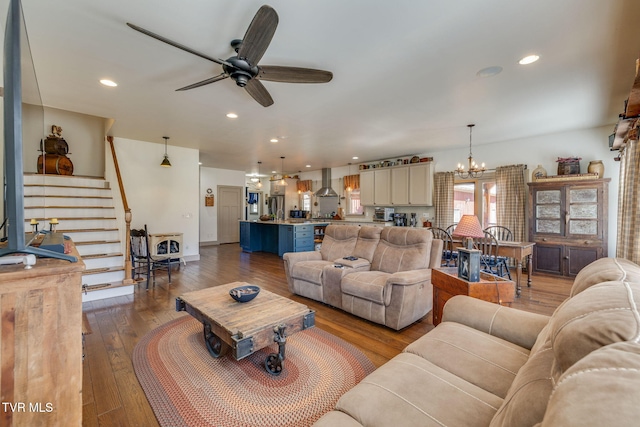 living area featuring ceiling fan with notable chandelier, recessed lighting, dark wood finished floors, and stairs