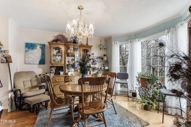 dining space with ornamental molding, light wood-type flooring, an inviting chandelier, and a textured ceiling