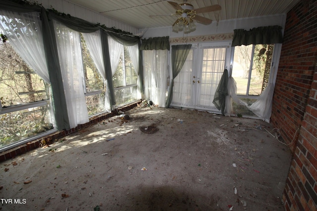 unfurnished room with a wealth of natural light, ceiling fan, and brick wall