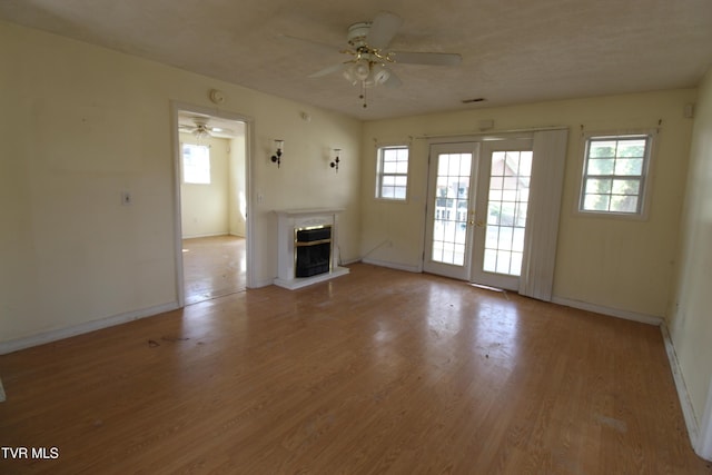 unfurnished living room featuring light hardwood / wood-style flooring, ceiling fan, and french doors