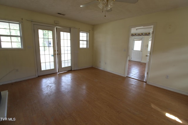 empty room with ceiling fan, french doors, and wood-type flooring