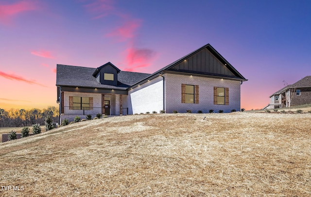 modern farmhouse with a porch, board and batten siding, and brick siding