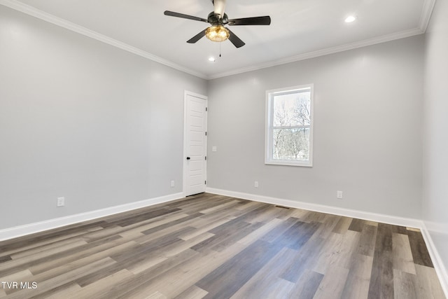 spare room featuring dark wood-type flooring, crown molding, baseboards, and a ceiling fan