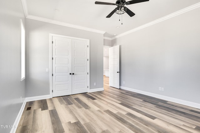 unfurnished bedroom featuring a closet, baseboards, wood finished floors, and ornamental molding