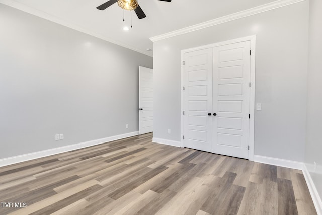 unfurnished bedroom with crown molding, a closet, baseboards, and wood finished floors