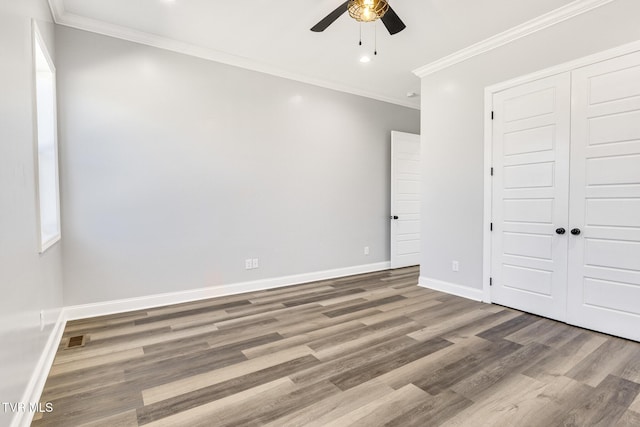 unfurnished bedroom with ornamental molding, wood finished floors, visible vents, and baseboards