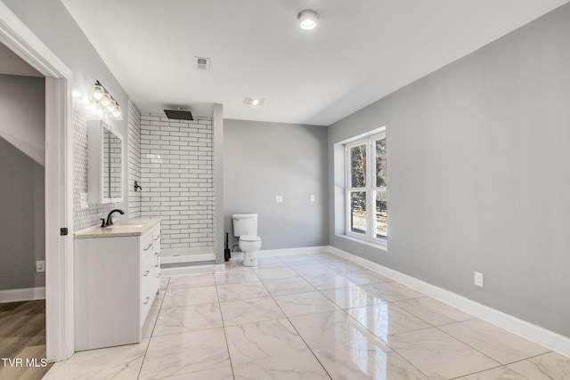 bathroom featuring vanity, visible vents, baseboards, marble finish floor, and tiled shower