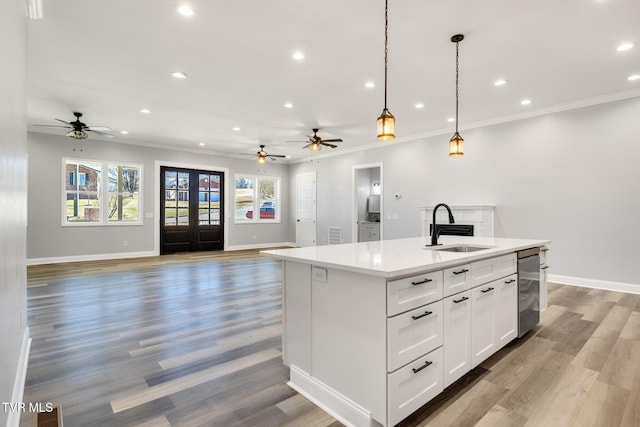 kitchen featuring open floor plan, ornamental molding, a sink, and a center island with sink