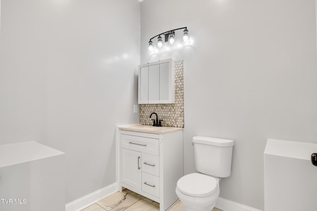 bathroom featuring marble finish floor, backsplash, toilet, vanity, and baseboards